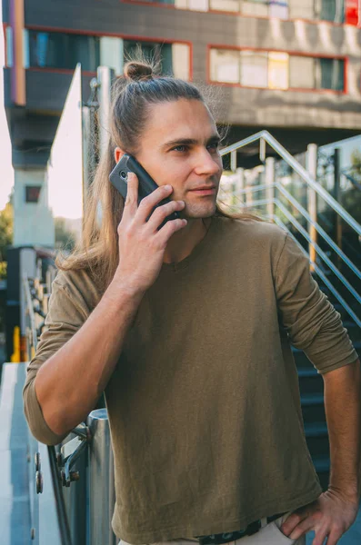 Attractive young man (hipster) talking on a smartphone while sit