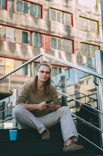 Attractive young man (hipster) writes a message on a smartphone