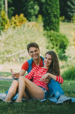 genç sevgi dolu çift parkta bir ekose üzerinde oturuyor, sarılma, 