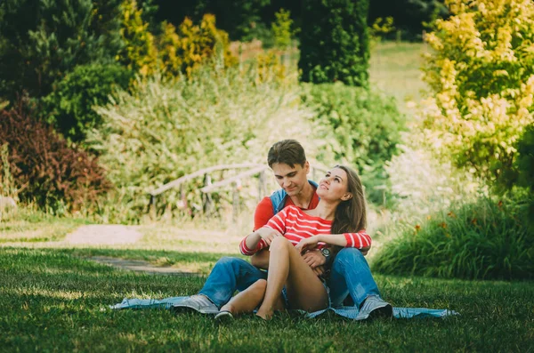 Jeune couple amoureux est assis sur un plaid dans le parc, étreignant , — Photo