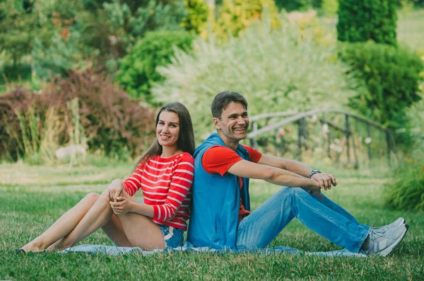 Giovane coppia innamorata è seduto sul plaid nel parco, indietro t — Foto Stock