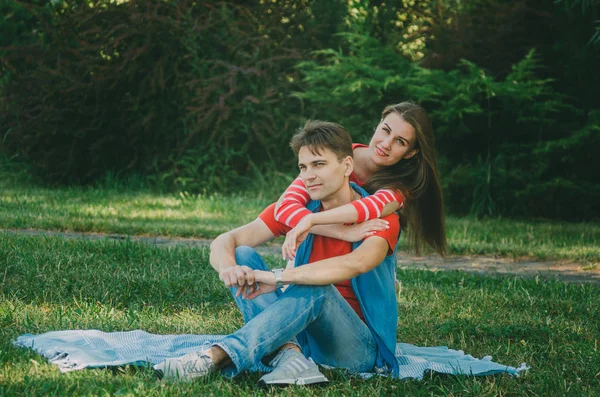 Junges Liebespaar sitzt auf einem Plaid im Park und umarmt sich, — Stockfoto