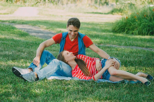 Young couple in love is sitting on a blanket in the park, the gi — Stock Photo, Image