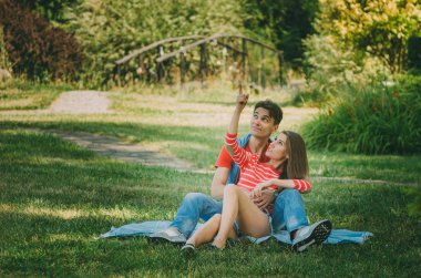 genç sevgi dolu çift parkta bir ekose üzerinde oturuyor, sarılma, 