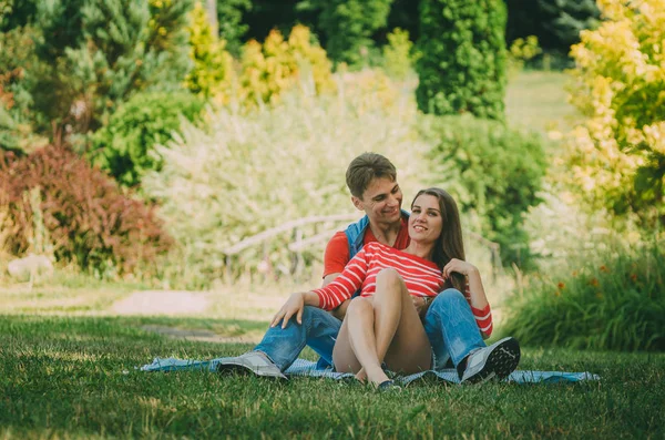 Genç sevgi dolu çift parkta bir ekose üzerinde oturuyor, sarılma, — Stok fotoğraf