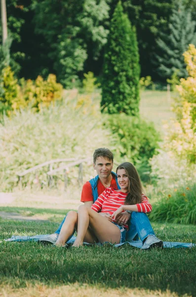 Ungt kärleksfullt par sitter på en Pläd i parken, kramas, — Stockfoto