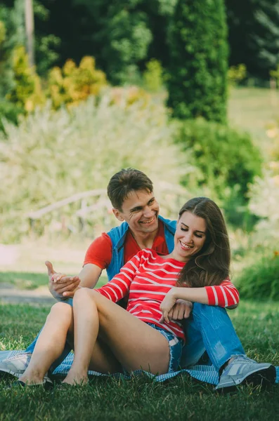 Jeune couple amoureux est assis sur un plaid dans le parc, étreignant , — Photo