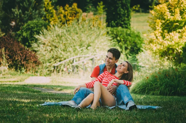 Jeune couple amoureux est assis sur un plaid dans le parc, étreignant , — Photo