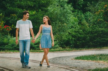 Parlak giysiler içinde güzel çift şehirde bir yaz parkında yürüyor. Temiz havada yürü. İki sevgilinin randevusu. Bir kadın için bir erkeğin kur dönemi, doğada romantik toplantılar
