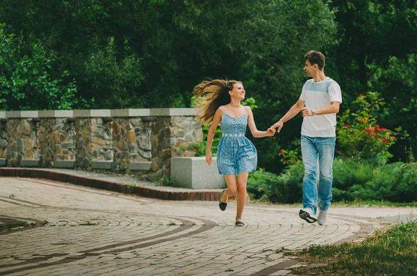 明るい服を着た美しいカップルは 市内の夏の公園を歩きます 新鮮な空気の中を歩く 二人の恋人のデート女性のための男性の求愛の期間 自然の中でロマンチックな会議 — ストック写真