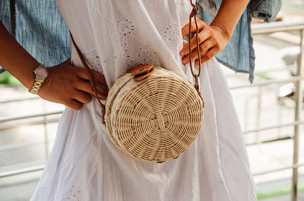 Chica delgada en un vestido de chintz blanco sostiene una ronda de paja tejida b —  Fotos de Stock