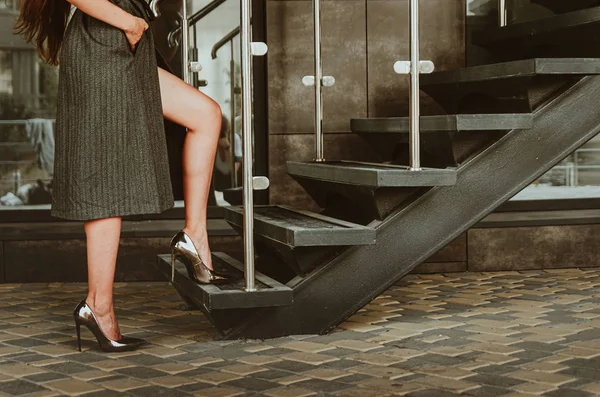 Smukke kvindelige ben i metal højhælede sko klatre op ad trappen - Stock-foto