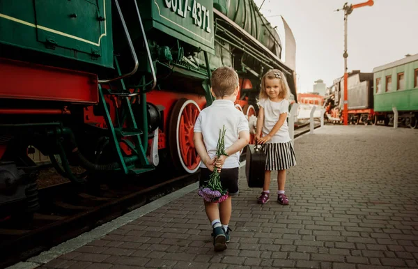 Un niño pequeño con un ramo en sus manos se encuentra con una linda chica con — Foto de Stock