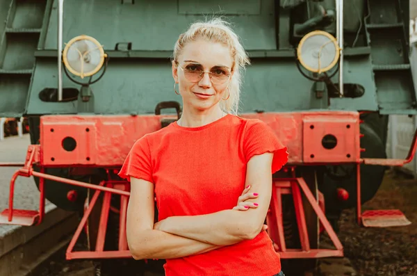 Woman in round stylish glasses stands in front of a train. Self- — Stock Photo, Image