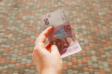 Kadın eli, arka planda 50 Hryvnia banknotu tutuyor..