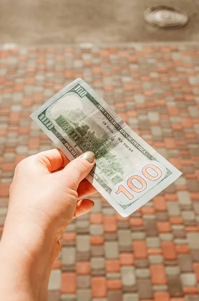 Női kéz tartja 100 dollár bankjegy hátterében a — Stock Fotó