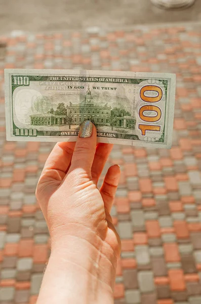 Mão feminina detém nota de 100 dólares contra o fundo do — Fotografia de Stock