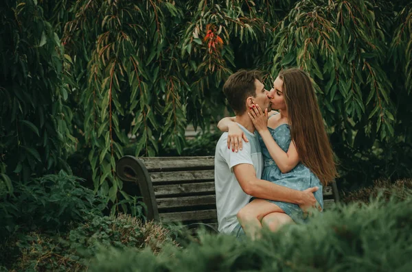 Vackra par i kärlek sitter i en park på en bänk på sommaren — Stockfoto