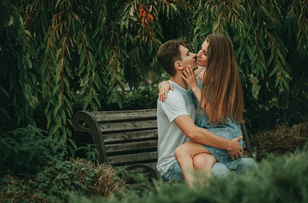 Hermosa pareja enamorada se sienta en un parque en un banco en el verano —  Fotos de Stock