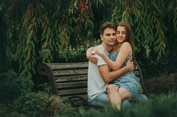 Mooi paar in liefde zit in een park op een bank in de zomer — Stockfoto