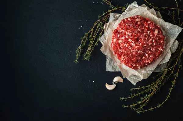 Färskt rått malet kött för köttbullar med kryddor på svart rygg — Stockfoto