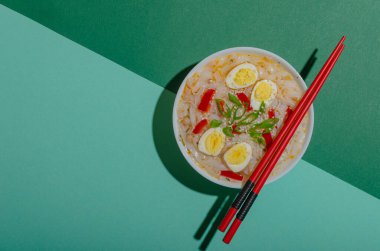 Yeşil arka planda ramen ve yumurtalı beyaz tabak. Pop sanat tarzında. Lezzetli Asya yemeği. Baharatlı yemek.