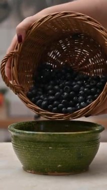 Kadın ellerinin sepetten mutfak masasındaki kaseye taze yaban mersini döktüğü yakın plan.