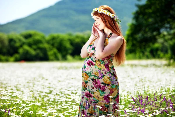 Schwangere Frau in der Natur mit Blumen. — Stockfoto