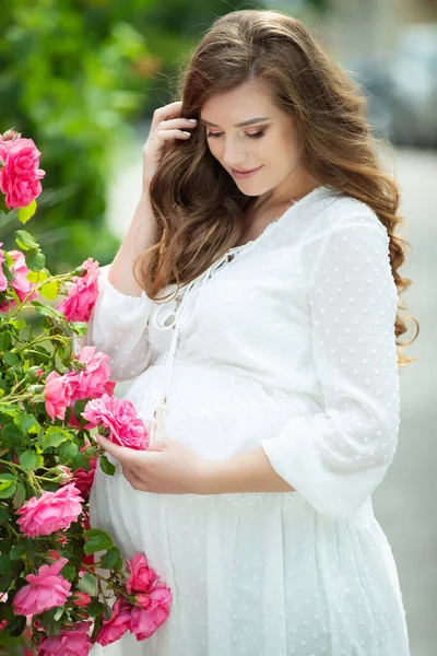 Zwangere vrouw in de natuur met bloemen. — Stockfoto
