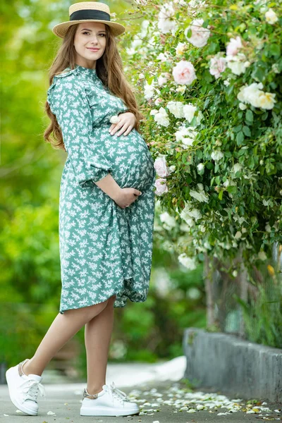 Zwangere vrouw in de natuur met bloemen. — Stockfoto