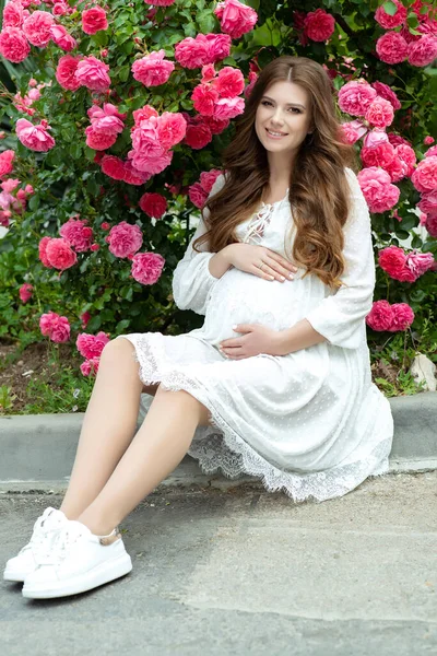 Zwangere vrouw in de natuur met bloemen. — Stockfoto