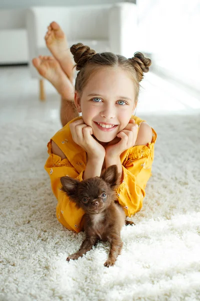 Un niño con un perro. Niñas juegan con un perro en la alfombra en casa . —  Fotos de Stock