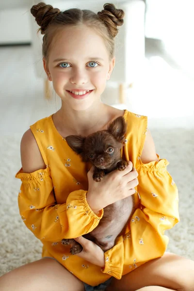 Ребенок с собакой. Маленькие девочки играют с собакой на ковре дома. — стоковое фото