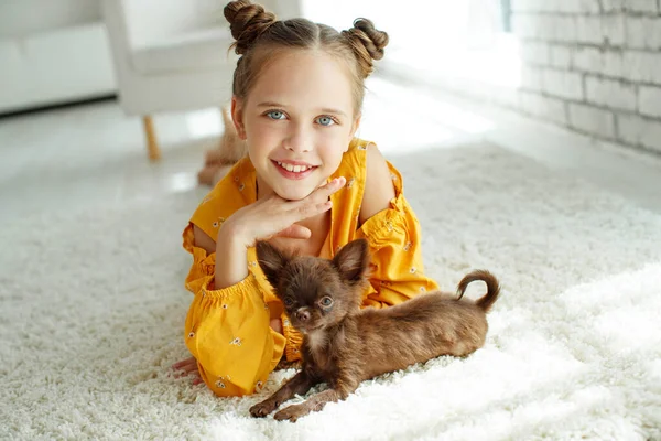 Un niño con un perro. Niñas juegan con un perro en la alfombra en casa . — Foto de Stock