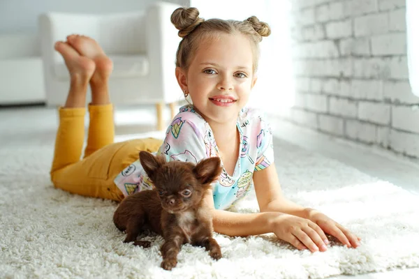 Un niño con un perro. Niñas juegan con un perro en la alfombra en casa . — Foto de Stock