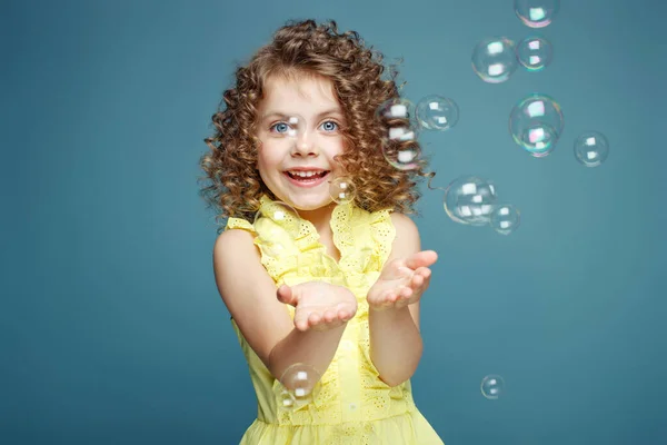 Child with soap bubbles. Little girl blowing soap bubbles in the studio.