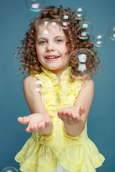 Kind met zeepbellen. klein meisje blazen zeepbellen in de studio. — Stockfoto