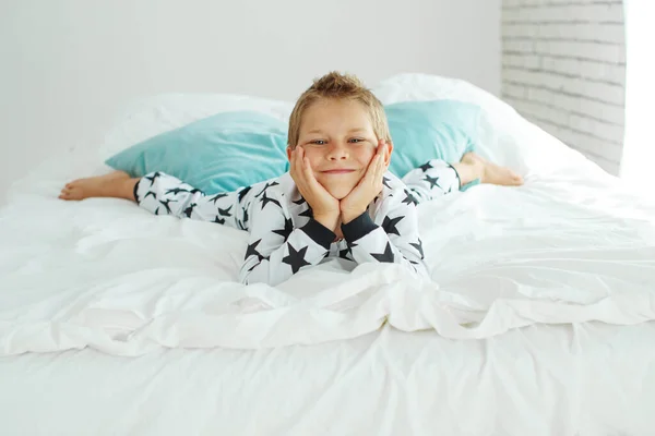 Bambino sul letto in pigiama. — Foto Stock