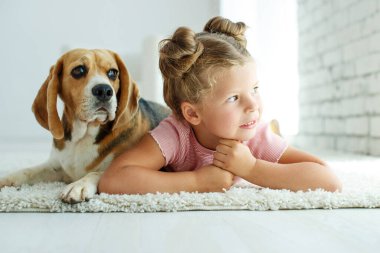 Köpekli bir çocuk. Küçük kız evde bir köpekle oynuyor. Çocuk ve hayvan.