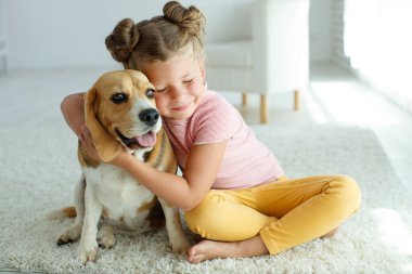 Köpekli bir çocuk. Küçük kız evde bir köpekle oynuyor. Çocuk ve hayvan.