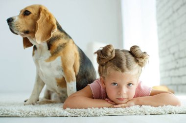Köpekli bir çocuk. Küçük kız evde bir köpekle oynuyor. Çocuk ve hayvan.