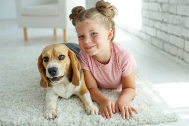 Köpekli bir çocuk. Küçük kız evde bir köpekle oynuyor. Çocuk ve hayvan.