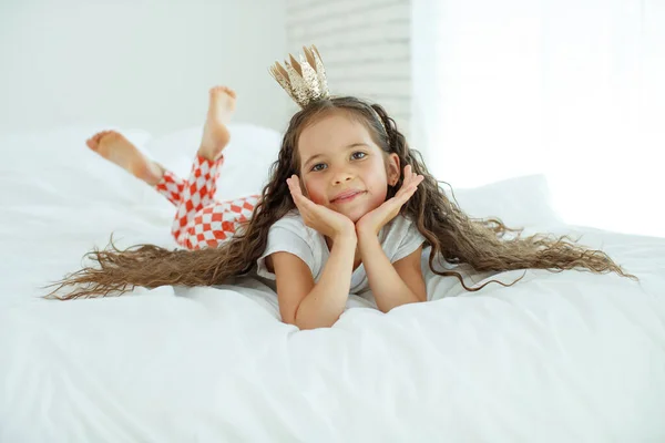 Niña en la cama. El niño en casa se despierta en la cama por la mañana. — Foto de Stock