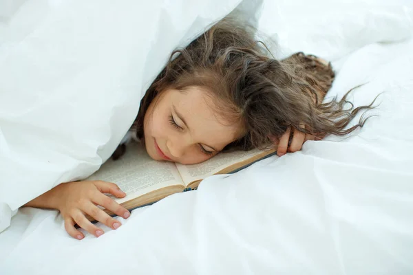 The child got tired of reading the book and fell asleep.