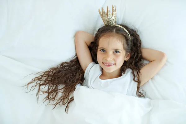 En liten flicka i sängen. Barnet där hemma vaknar i sängen på morgonen.. — Stockfoto