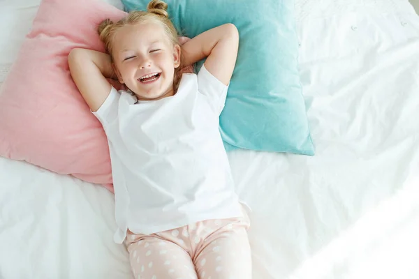 Dziewczynka w łóżku z białą pościelą. Dziecko w domu rano budzi się w swoim pokoju.. — Zdjęcie stockowe