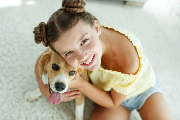 Ребенок с собакой. Девочка-подросток с собакой-ищейкой дома. — стоковое фото