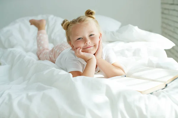 Ragazzina a letto con biancheria bianca. Un bambino a casa la mattina si sveglia nella sua stanza. — Foto Stock