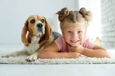 Köpekli bir çocuk. Küçük kız evde bir köpekle oynuyor. Çocuk ve hayvan.
