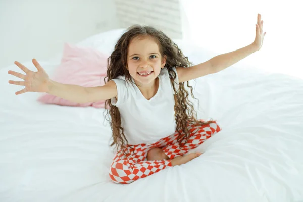 Niña en la cama. El niño en casa se despierta en la cama por la mañana. — Foto de Stock